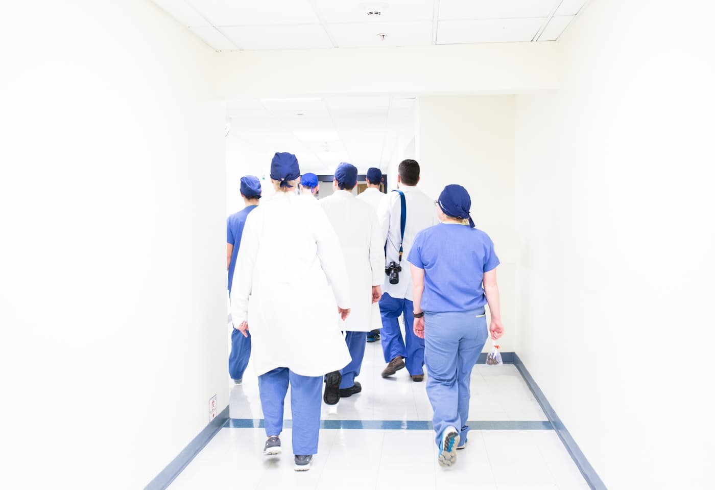 Medical team in scrubs and coats walking through a hospital hallway