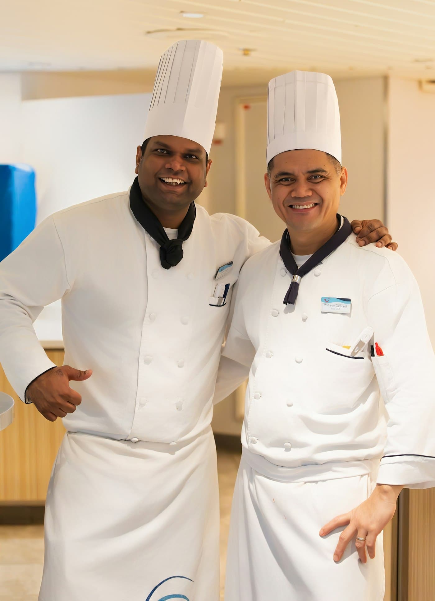 Two chefs in white uniforms and toques smiling together